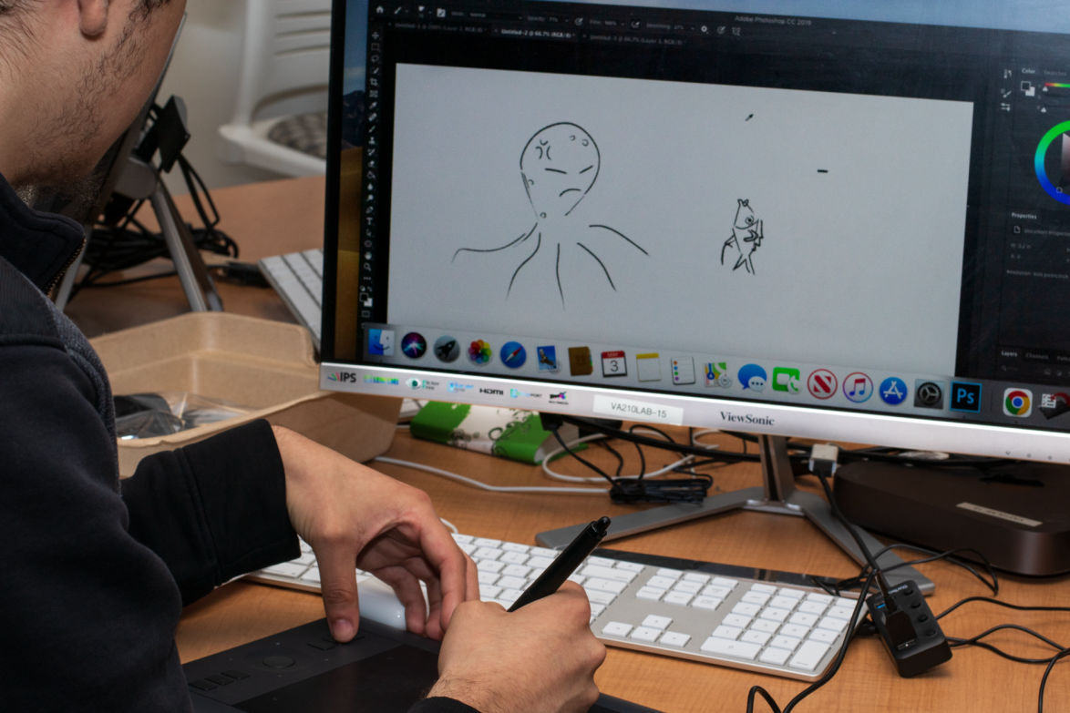 student sketching on wacom tablet with art on computer screen